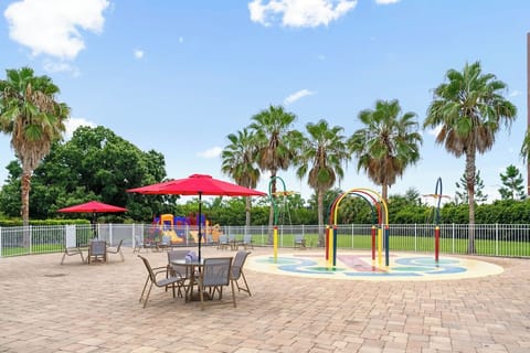 Gather under red umbrellas while little ones splash nearby.