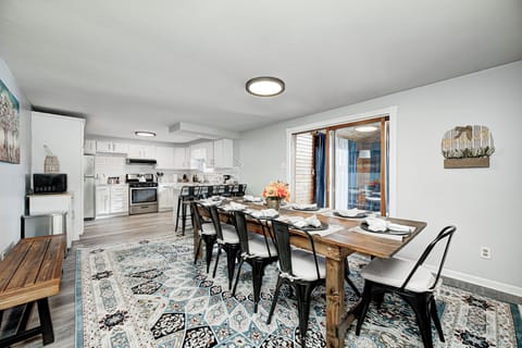 Bright open dining/kitchen with farmhouse table, modern kitchen, and sunroom
