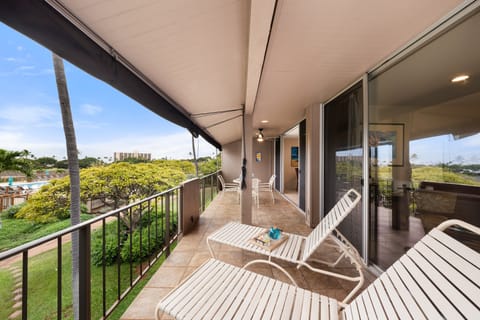 Spacious lanai featuring comfortable lounge chairs and a shaded area for relaxing in a serene tropical setting.