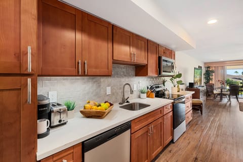 Fully equipped kitchen featuring rich wood cabinetry, stainless steel appliances, and a sleek tile backsplash