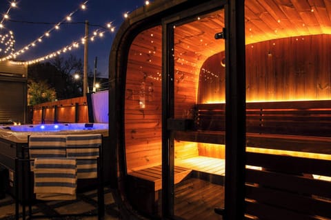 Outdoor spa retreat featuring a glowing Scandinavian-style sauna and relaxing hot tub—perfect for unwinding under the string lights at night.