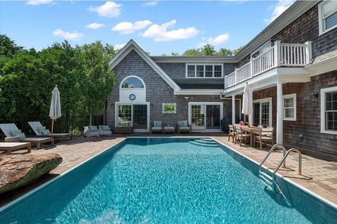 Classic shingle exterior framing a sparkling heated saltwater pool.