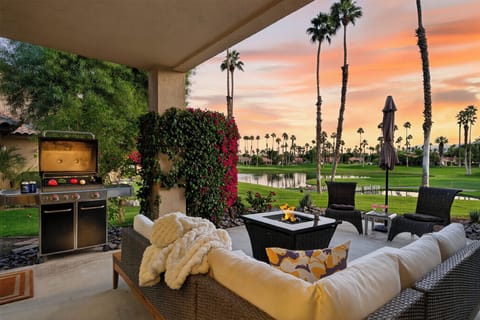 Covered patio lounge with a modern fire pit and sunset golf course views.