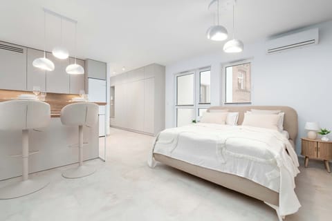 Bright interior with a comfortable bed and a kitchenette arranged in one cohesive space creates a light, airy atmosphere perfect for both relaxation and everyday living.