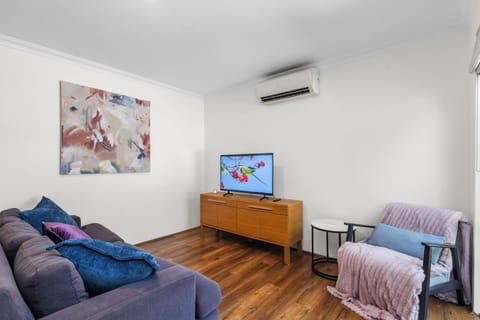 Comfortable living area with TV, plush sofa, air conditioning, and a relaxing reading chair.