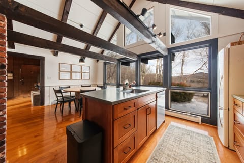 Bright, open kitchen with island seating and wooded views