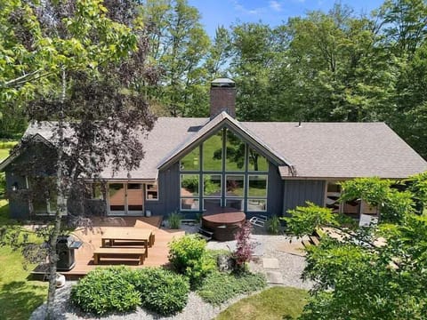 Soak in the private hot tub while taking in peaceful woodland views and the home’s striking architec