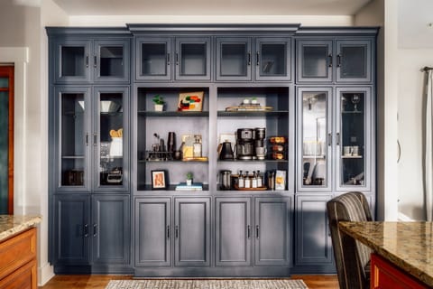 Floor-to-ceiling coffee and cocktail wall stocked with syrups, mugs, glassware, and bar tools—wake up to your perfect latte and wind down with a crafted nightcap without ever leaving the house.