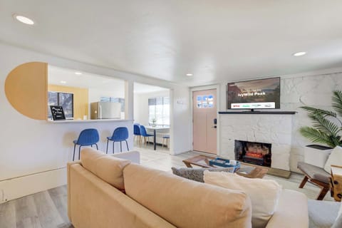 Relax in the inviting living room which features a tan sofa and a 55 inch Smart TV mounted above a white stone fireplace. The open layout and modern design create a warm atmosphere perfect for movie nights in your mountain retreat.