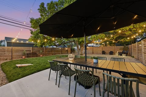 Private backyard patio with string lights, dining table, and fire pit