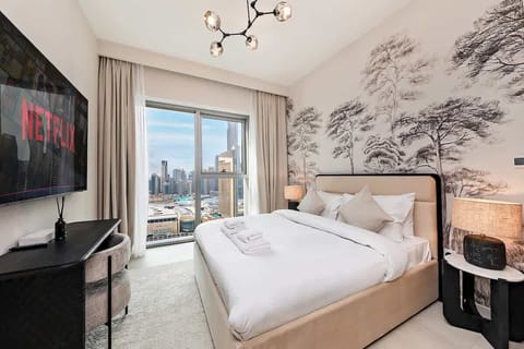 Sink into the plush queen bed dressed in soft, high-quality linens, surrounded by warm, ambient lighting that creates a cozy, inviting atmosphere. A huge window fills the room with natural light and offers stunning views of iconic Dubai city skyline