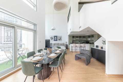 Inviting dining area offering open views of the living room and floor-to-ceiling windows with a breathtaking city backdrop