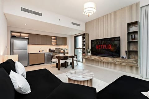 Modern living room designed for comfort and fun, with a cozy sofa, TV, game console, and panoramic downtown windows