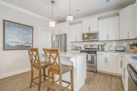 Modern kitchen featuring a large island with bar seating, stainless steel appliances, granite countertops, and plenty of cabinet space.