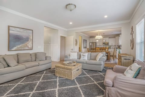 Open main living area featuring comfy seating and seamless flow into the dining room and kitchen, Its the perfect space for families to gather, relax, and enjoy time together.