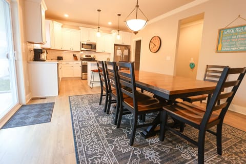 Kitchen and dining area featuring white cabinetry, stainless steel appliances, a large center island, and a wooden dining table.