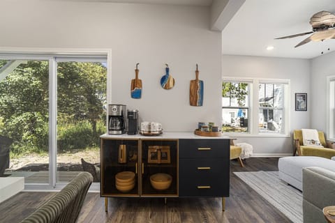 A stylish coffee and beverage station featuring a drip coffee maker and Keurig, beautifully displayed on a modern cabinet with warm wood accents. Sliding doors open to the backyard.