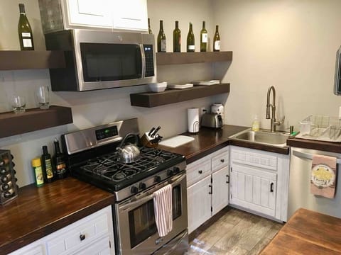 This stylish kitchenette ensures all your cooking needs are met, featuring a full stainless steel gas range, a large sink, and gorgeous dark wood countertops. Charming floating shelves provide easy access to wine and glassware.