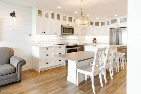 Kitchen island and dining area with white chairs and a wooden table, perfect for meals and gathering.
