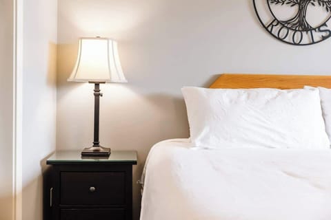 A serene space with a white bed, nightstand, and lamp, offering a calm, restful atmosphere.