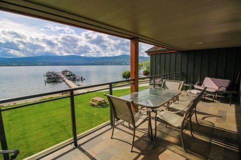 A wider balcony with black metal railings, outdoor seating, and a view of water and mountains, perfect for enjoying the bright sky.
