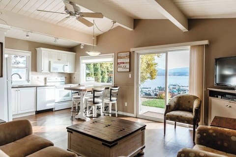 Bright kitchen and dining area with lake views, a wooden dining table, chairs, and a kitchen island with bar stools.