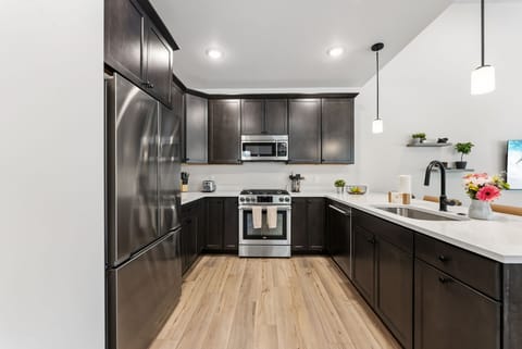 Your modern kitchen features sleek dark cabinetry, stainless steel appliances, and bright quartz countertops—perfect for preparing meals during your stay.