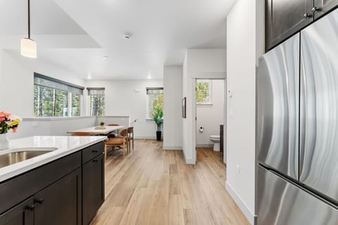 Your modern open-concept space flows seamlessly from kitchen to dining, bathed in natural light from forest views.