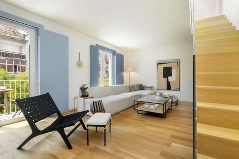 Stylish living room with a modern design, featuring a cozy sectional sofa, a sleek chair, and large windows for natural light. Perfect for relaxing or entertaining in a bright, open space. The living room has 3 french balcony with seatings. 