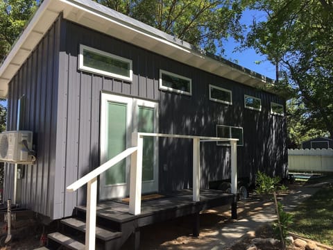 This stylish, compact guest house provides a completely private escape. It features a sleek, modern exterior with dark metal siding and its own private deck, offering a unique and comfortable stay surrounded by nature.