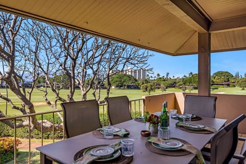 Shaded lanai dining area overlooking manicured green grounds, offering a peaceful setting for relaxed outdoor meals.
