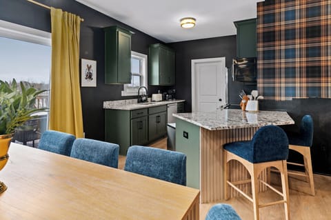 Chef’s kitchen with emerald cabinetry and granite countertops, designed for gathering, cooking, and entertaining