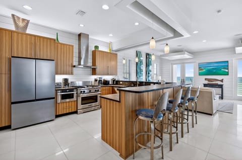 2nd Floor - Gourmet chef’s kitchen with professional gas range, stainless steel appliances, and expansive prep space—perfect for cooking meals together while enjoying stunning Gulf-front views and open-concept living.