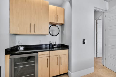 1st Floor - Gulf-front King suite with wet bar and mini fridge, 2 custom wall mounted arcades, private ensuite bathroom with walk-in shower, and direct access to the pool deck—perfect for relaxing in luxury just steps from the beach and emerald waters.