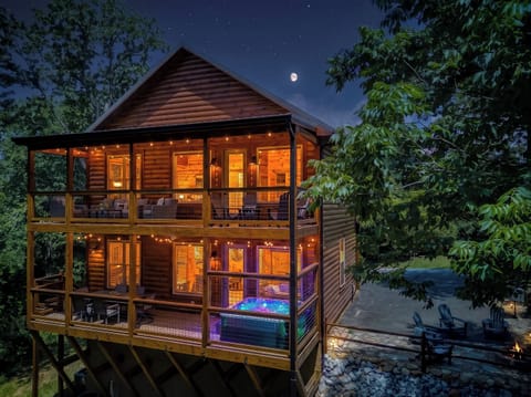 Cozy treehouse-style cabin with hot tub, fire pit, and glowing balconies