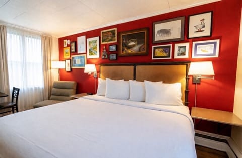 A bright bedroom with one king bed, crisp white linens, and a convenient in-room kitchenette.