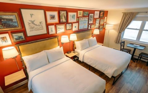 A bright bedroom with two full sized beds, crisp white linens, and a convenient in-room kitchenette.