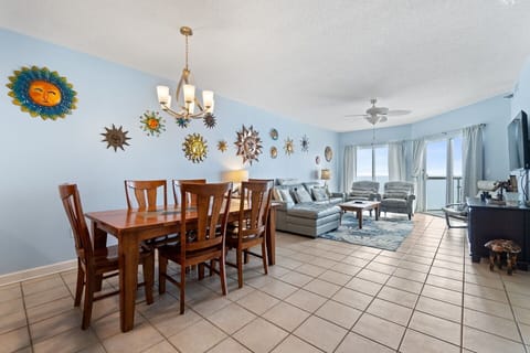 Bright living and dining area with ocean views and unique sun-themed wall decor.