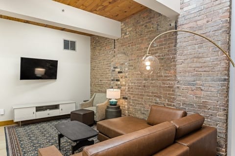 Settle into the leather sectional beneath warm, rustic brick.