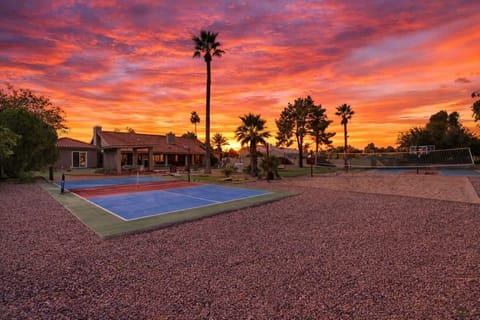 Private backyard packed with fun, featuring a sparkling pool with a waterslide, two hot tubs, sun loungers, mini golf, a gazebo with a lounge area and Smart TV, a fire pit surrounded by outdoor seating, plus sports courts.