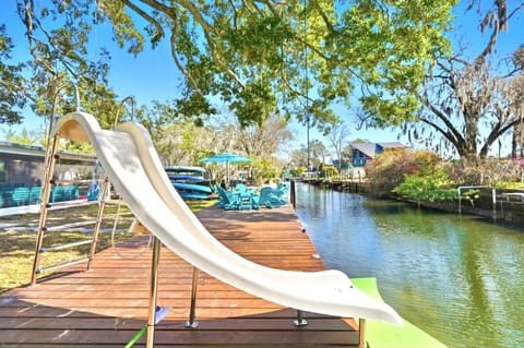 A private waterfront dock featuring a waterslide that leads directly into the springs, creating endless fun for guests of all ages. The dock is surrounded by ample seating, shaded by mature trees, and overlooks the peaceful, crystal-clear water—making it 