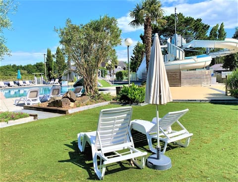 Relaxation awaits on the sun loungers by the pool, nestled in green gardens with a view of the adventurous water slide.