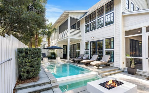 Elegant home features a private pool and fire pit surrounded by tropical landscaping for ultimate relaxation.