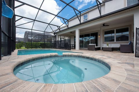 Step outside to a beautiful private pool area with a sparkling jacuzzi, inviting you to unwind. The screened-in space and smooth stone patio create a relaxing atmosphere, complemented by bright blue skies for sunny days ahead.