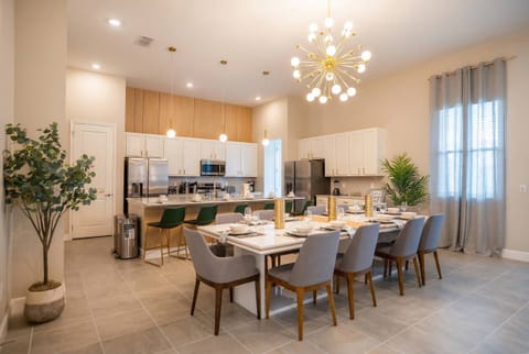 Enjoy a spacious dining area with a sleek table for six, stylish upholstered chairs, and abundant natural light from large windows. The warm wood accents and modern chandelier create a welcoming atmosphere for memorable meals.