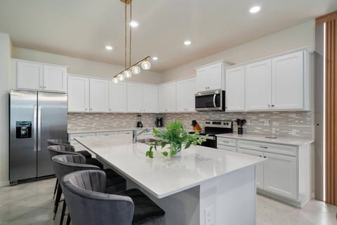 Welcome to this inviting kitchen featuring sleek white cabinetry and a spacious island that inspires creativity. Stylish pendant lights above elegant gray bar stools create a warm ambiance, ideal for casual meals or your morning.