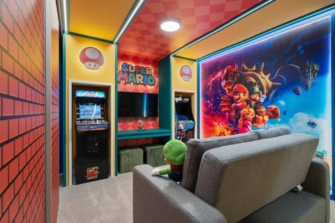 Step into this vibrant game room, adorned with bold colors and eye-catching graphics that celebrate classic gaming. The plush gray sofa invites you to unwind while the arcade machines promise hours of entertainment for all ages.