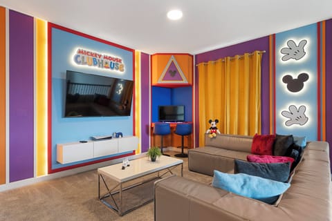 Experience a lively living area filled with playful colors, where a cozy sectional sofa with colorful pillows invites you to relax. Bold wall designs and warm lighting set the perfect backdrop for enjoyable family gatherings.