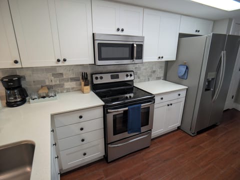 Kitchen with solid surface, stainless appliances, hand towels, and oven mitts