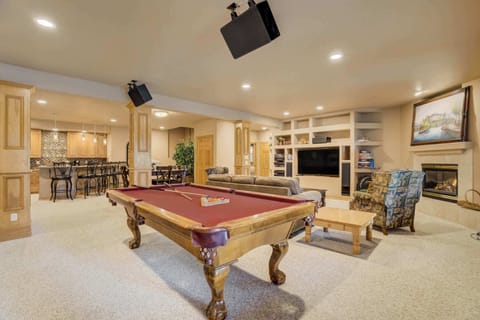 Welcome to Peaceful Pines! Step into an expansive lounge designed for both entertainment and relaxation. Large windows flood the space with natural light and provide peaceful views of the surrounding pines, creating a warm mountain atmosphere.